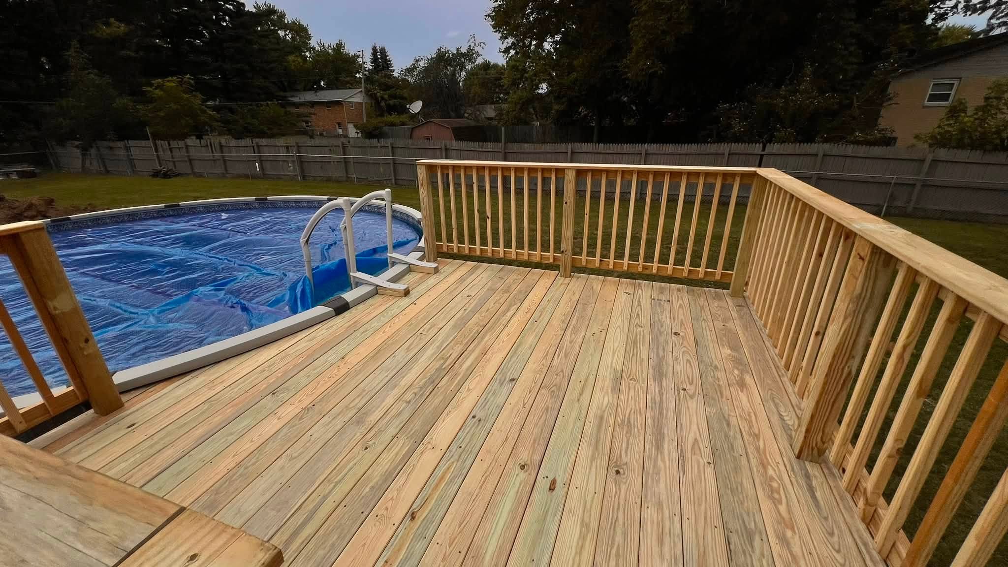 New pressure-treated wood pool deck with railing around an above-ground pool