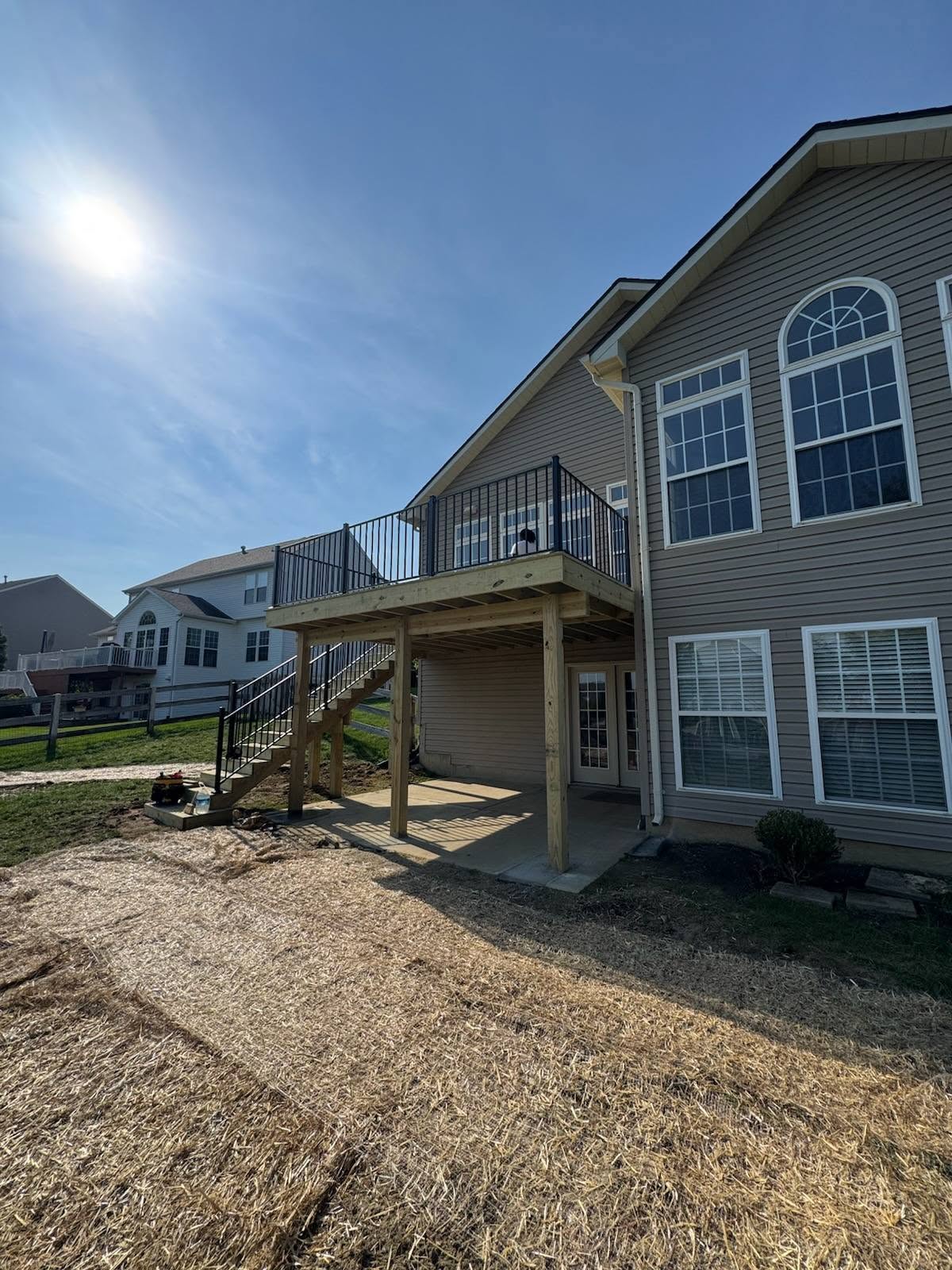 Elevated wood deck with stairs and covered patio below at a two-story home